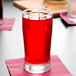A Libbey highball glass filled with red liquid and a lemon slice on the rim.
