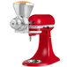 A red and silver KitchenAid grain mill attachment.