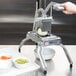 A person using a Nemco Easy Onion Slicer II to cut vegetables into a bowl.