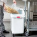 A man using a Rubbermaid ingredient bin to store a bag of noodles.