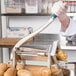 A person in a white coat using a Vollrath 3/8" French Fry Cutter to cut a potato.