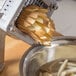 A Vollrath potato peeler cutting potatoes into a bowl.