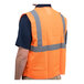 A person wearing a Cordova orange high visibility safety vest with reflective stripes.