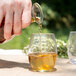 A hand pouring brown liquid into a Chef & Sommelier rocks glass.