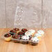 A clear plastic InnoPak container holding cupcakes with white and chocolate frosting and sprinkles.