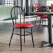 A Lancaster Table & Seating Hairpin Chair with a red vinyl seat and black metal legs at a table in a restaurant.