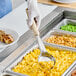 A hand wearing a glove uses an ivory Vollrath Jacob's Pride Spoodle to serve food.