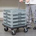 A man pushing a Vollrath Traex rack dolly with a stack of crates.