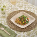 A Bambu Veneerware square bamboo plate with food on a table.