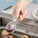 A person using Cambro plastic tongs to scoop potatoes from a pan.