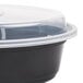 A black Pactiv Newspring VERSAtainer oval microwavable container with a clear lid.