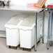 An Advance Tabco stainless steel work table with open base holding two white plastic containers.