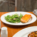 A Reserve by Libbey Aluma White medium rim porcelain platter with food on a table.