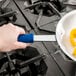 A hand using a blue Vollrath Cool Handle II on a frying pan.