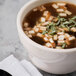 A Libbey St. Francis bouillon cup filled with soup topped with meat and herbs.