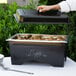 A person using a Sterno ChalkBoard Chafer with food on a table.