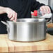 A person pouring liquid into a Vollrath silver brazier.