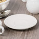 A Libbey ivory porcelain saucer under a white cup on a table.