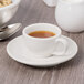 A Libbey ivory porcelain saucer with a cup of tea on it.