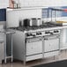A large stainless steel Garland commercial gas range with two ovens on a counter in a professional kitchen.