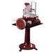 A red and white Omas Volano meat slicer on a pedestal stand with a wheel.
