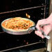 a hand holding a pizza in an oven