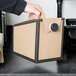 A person's hand holding a brown and black cardboard box with a black circle on it.