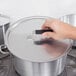 A hand with a black Torogard handle on a metal pot lid.