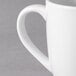 A close-up of a white Tuxton Milano china mug with a handle.
