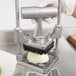 A person using a Nemco vegetable dicer to chop an onion.