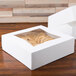 Two white auto-popup bakery boxes with cookies inside on a table.