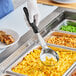 A person holding a Vollrath black solid round spoodle over macaroni and cheese.