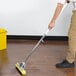 A hand using a Carlisle foam sponge mop to clean a hardwood floor.