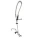 A chrome Equip by T&S wall mounted pre-rinse faucet with black metal accents.
