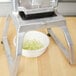 A Vollrath Redco InstaCut 3.5 dicing blade assembly on a table with a bowl of chopped onions.