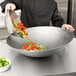 A chef using a Town hand hammered Cantonese wok to cook vegetables.