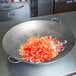 A large Town hand hammered Cantonese wok filled with chopped onions and peppers.