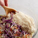 A bowl of shredded cabbage and carrots with white salad dressing.