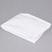 A folded white L.A. Baby crib sheet on a gray surface.