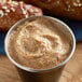 A wooden table topped with a cup of Admiration Dusseldorf Mustard.