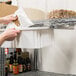 A person's hand adjusts a Metro Super Erecta shelf using a plastic bag.