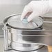 A hand in a white glove using a Robot Coupe food processor.