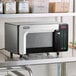 An Amana commercial microwave on a counter with food inside.