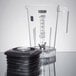 A clear Waring blender jar with a lid and a measuring cup on a counter.