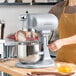 A silver Hobart N50 5-quart bowl lift countertop mixer with a stainless steel mixing bowl and whisk attachment, shown in use on a kitchen counter.