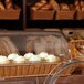 A rectangular clear polyweave cover on a basket of cupcakes in a bakery display.