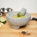 A Fox Run Granite Mortar and Pestle with lime and garlic inside.