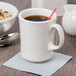 A white Libbey porcelain cafe mug with a red straw in it.