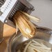 A Vollrath French fry cutter being used to cut potatoes on a counter.