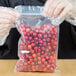 A person in gloves holding a LK Packaging plastic bag of cranberries.